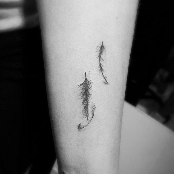 small-black-feather-tattoo-on-arm